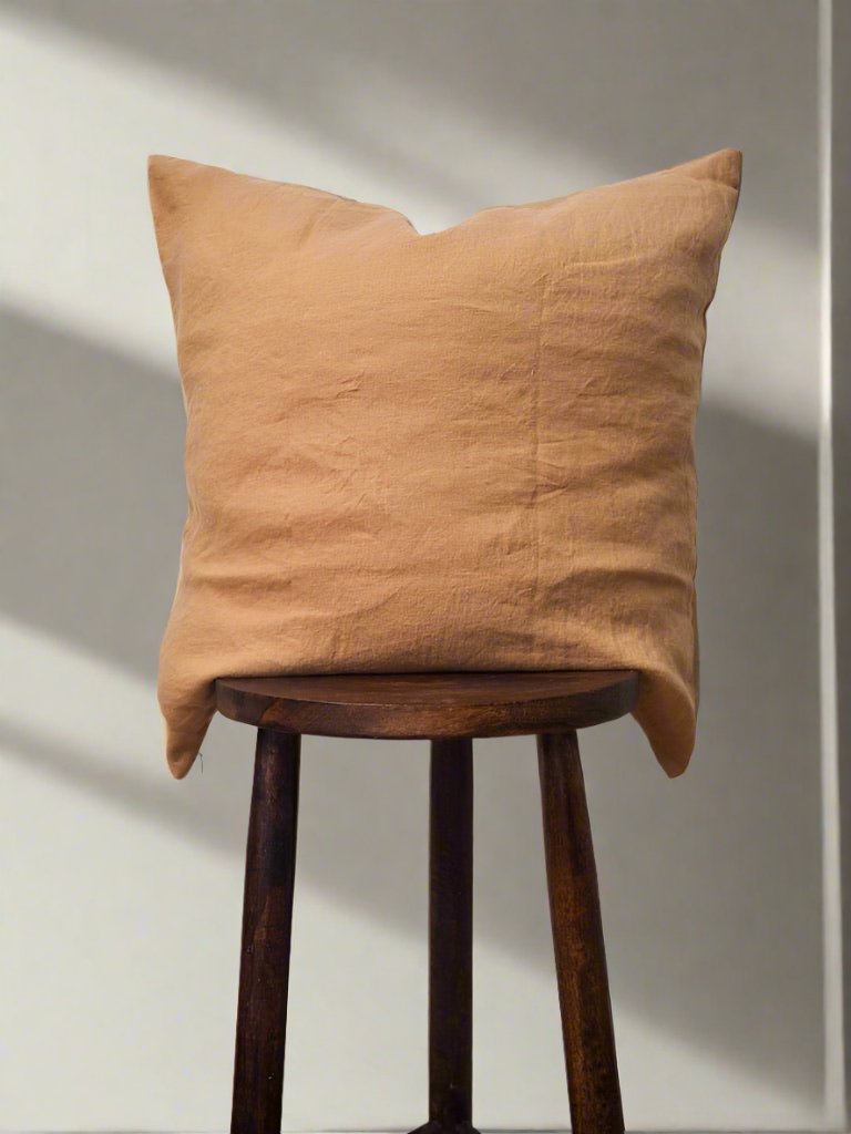 Linen Cushion Cover in Terracotta - TSL, placed on a a stool 
