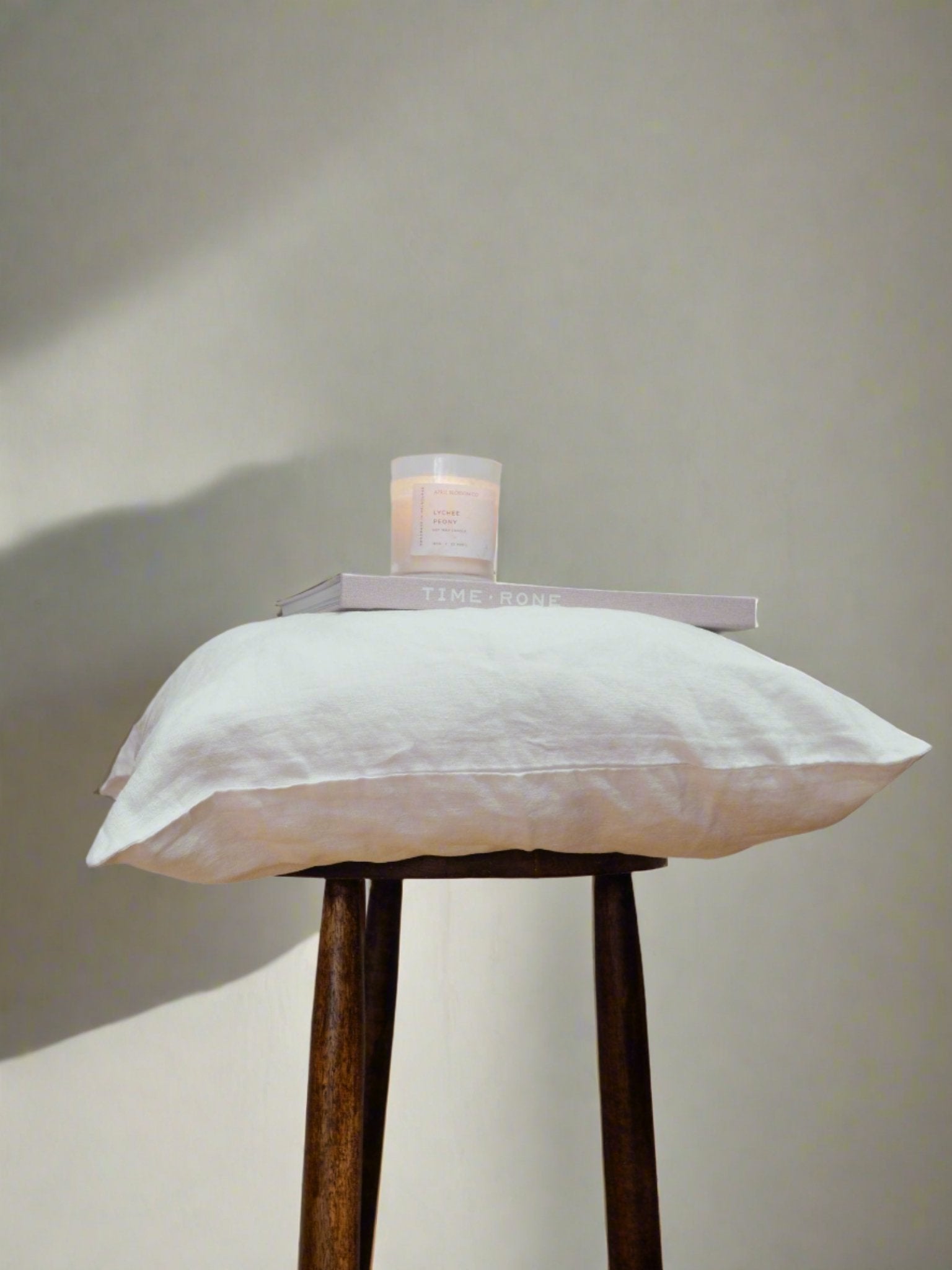 Linen Cushion Cover in White - TSL, cushion cover on a stool with book and candle displayed on top 